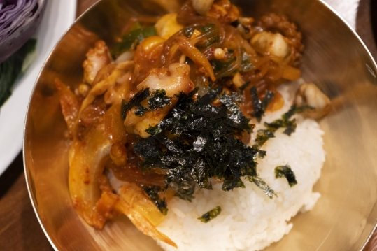 놋그릇 흰 밥 위에 낙지볶음을 얹고 김가루를 뿌린 모습